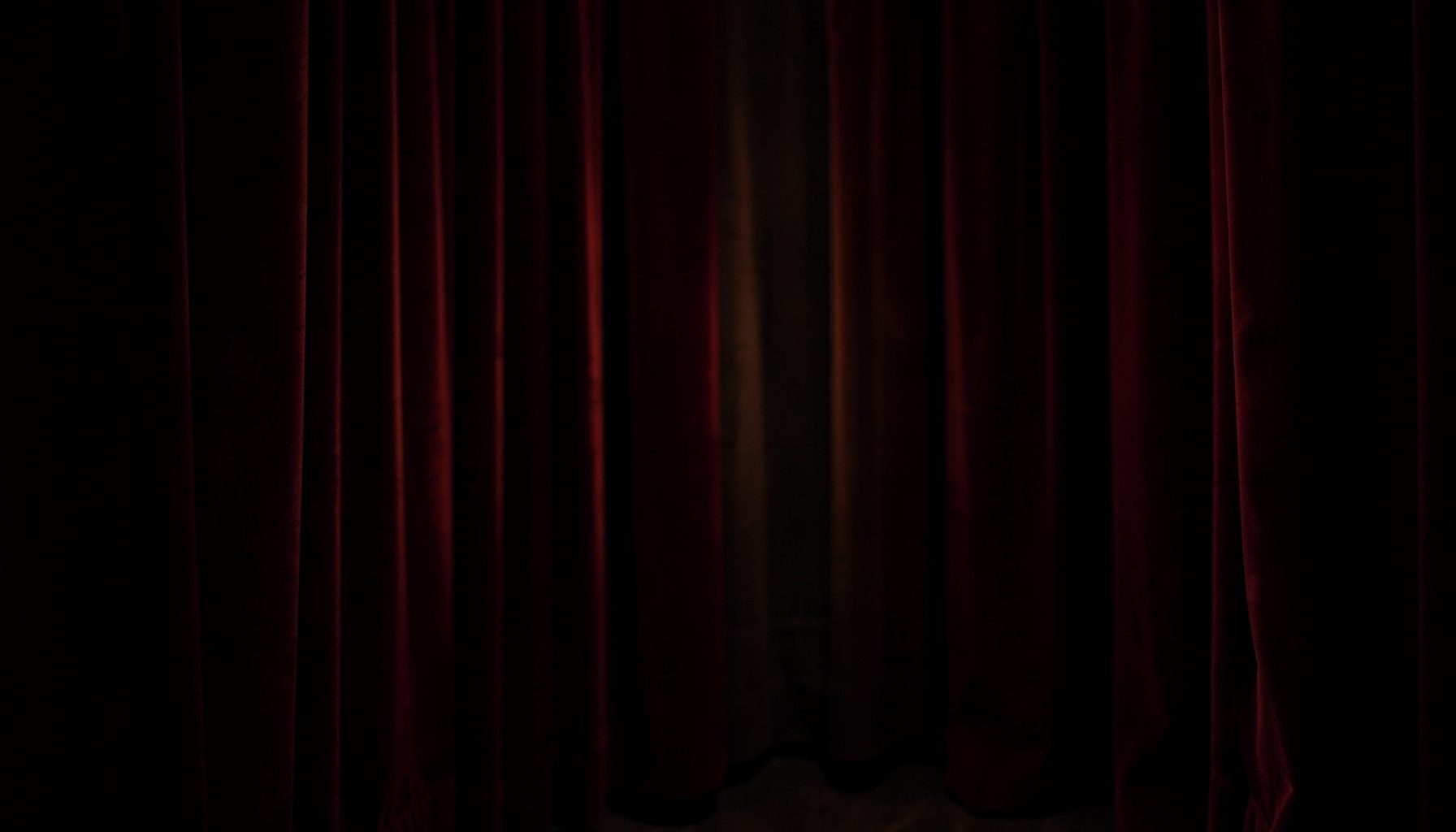 Softly lit interior with deep burgundy velvet drapes and warm amber glow, creating an intimate and luxurious atmosphere